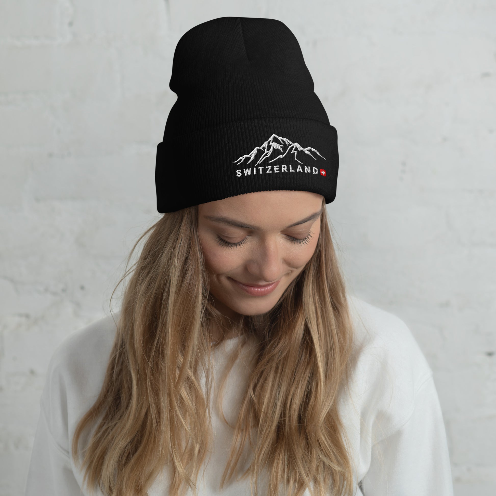 Black alpine-inspired beanie showcasing Swiss flag and mountain range design